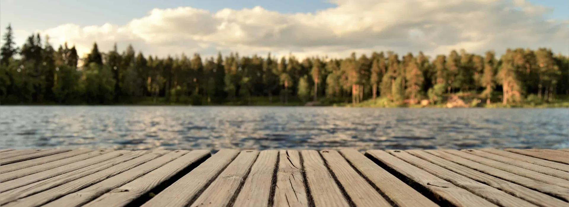 Drewniany pomost nad spokojnym jeziorem otoczonym drzewami